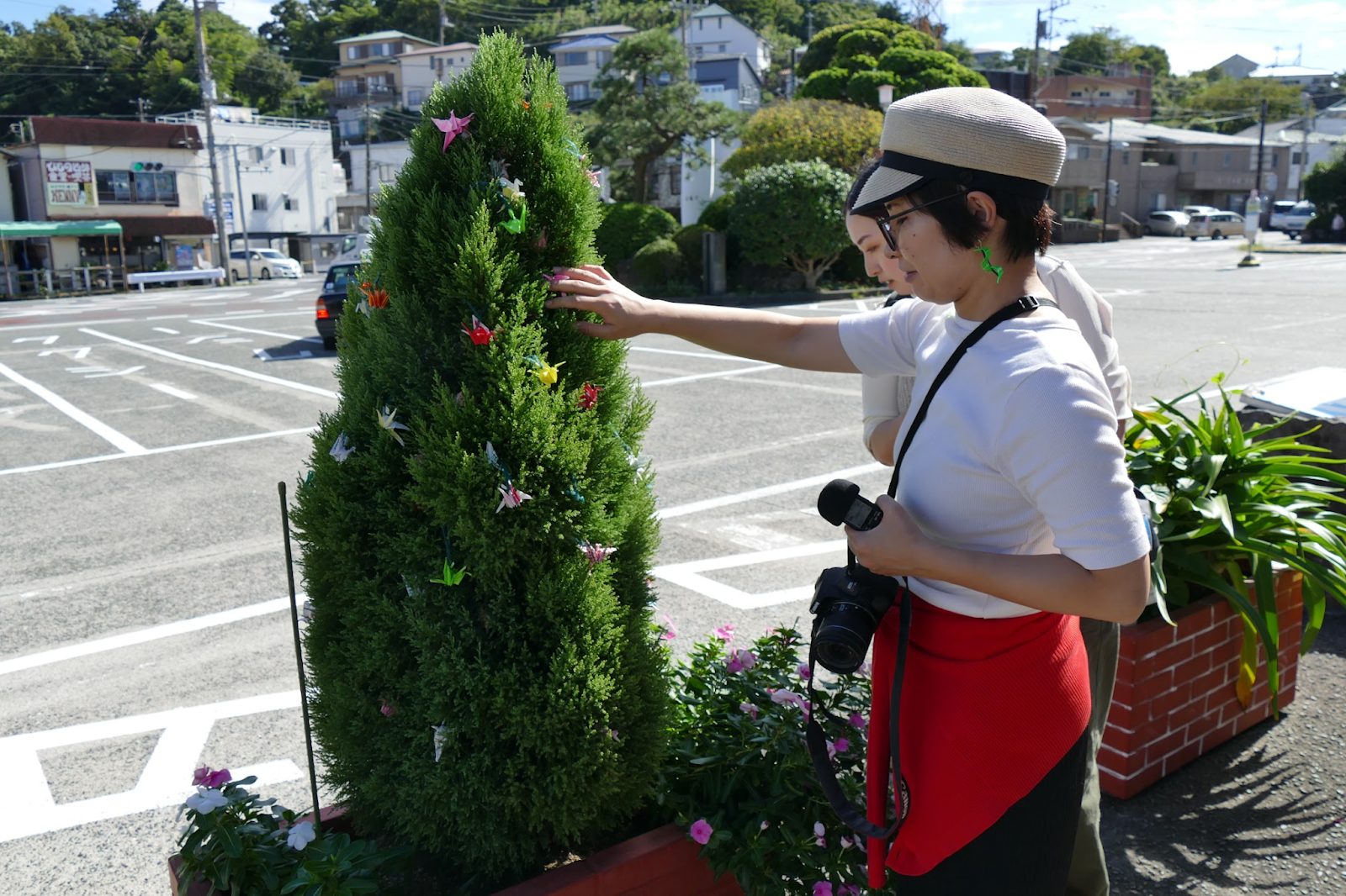 植木にたくさんの折り鶴が飾られている写真